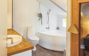 Ein Badezimmer mit Holzbadezimmer-Möbeln, einer Toilette und einer freistehenden Badewanne.