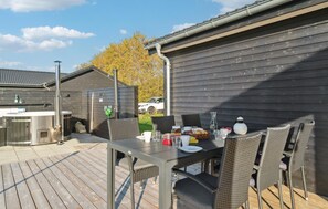 Une terrasse extérieure avec une table dressée pour le repas, entourée de chaises en osier.