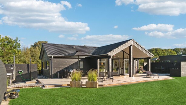 Une maison moderne dotée d’un patio couvert, d’une cour clôturée et d’une pelouse bien entretenue.