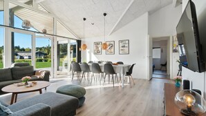 Un grand espace de vie comprenant une table à manger, des canapés et un téléviseur.