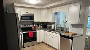 Una cocina moderna con armarios blancos, electrodomésticos de acero inoxidable y piso de madera.