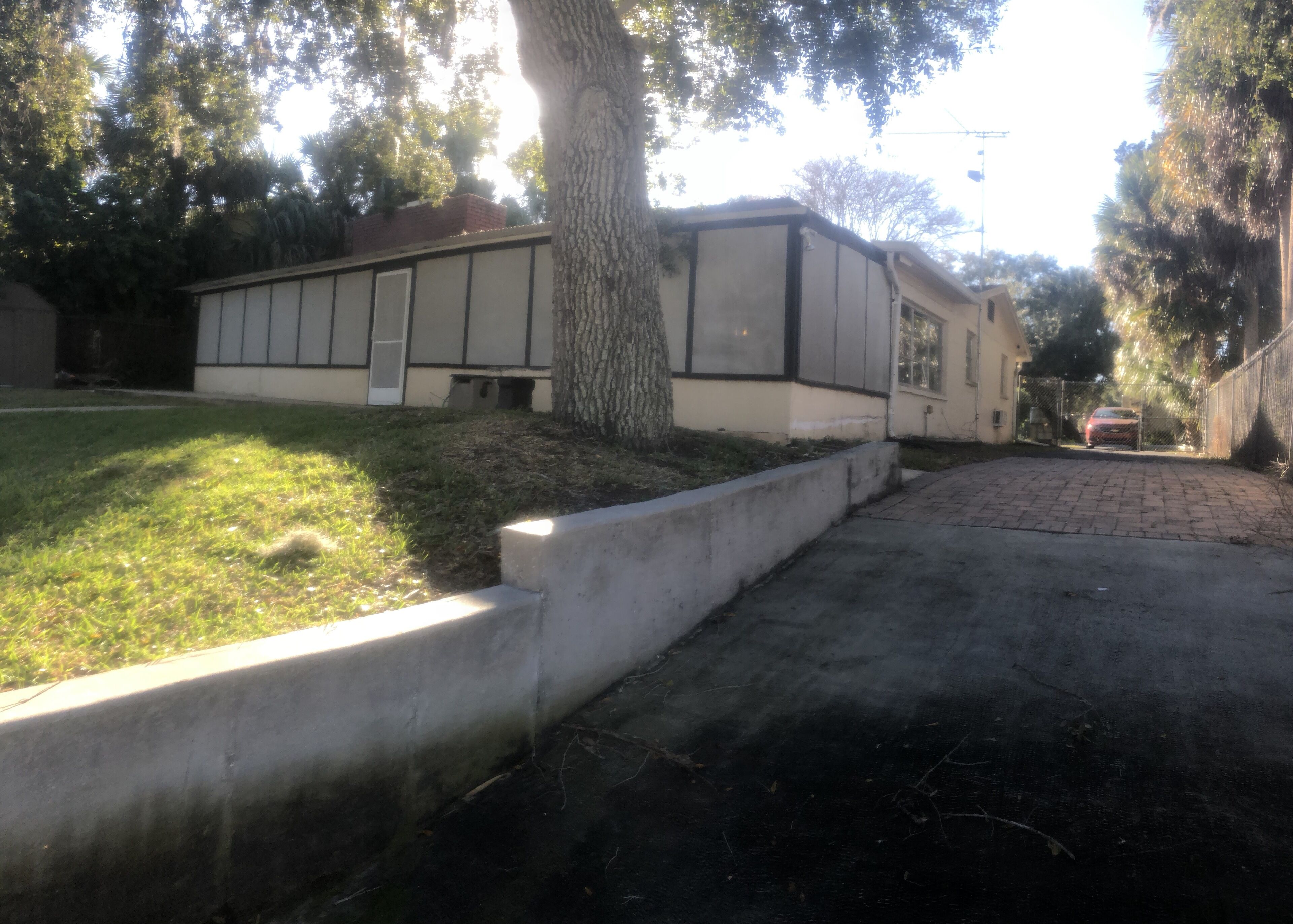 Un immobile residenziale con vialetto in pietra, prato e un albero.