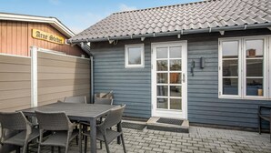 A patio with a table and chairs, a blue house with a tiled roof, and a sign reading "Arne Steet". - Stunning home in Nexø with WiFi (Nexø)
