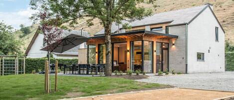 A modern house with a covered patio, a garden, and a croquet court.