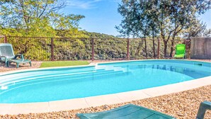 A swimming pool with a wooden deck, surrounded by pebbles and a metal fence. - Awesome home in Cabrerolles (Cabrerolles)