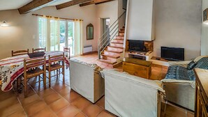 A cozy living room with a dining area, a staircase, a fireplace, and a TV. - Awesome home in Cabrerolles (Cabrerolles)