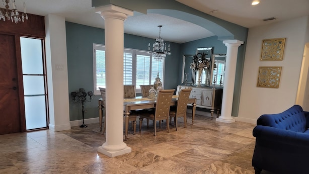 A spacious dining area with a marble floor, a chandelier, and a blue sofa. -  Luxury Estate with Dual Pools on 2.5 Acres Near Downtown Sarasota & Beaches (Sarasota)