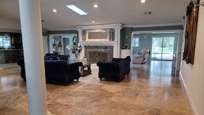 A spacious lobby with a marble floor, two dark armchairs, a fireplace, and a large mirror. -  Luxury Estate with Dual Pools on 2.5 Acres Near Downtown Sarasota & Beaches (Sarasota)