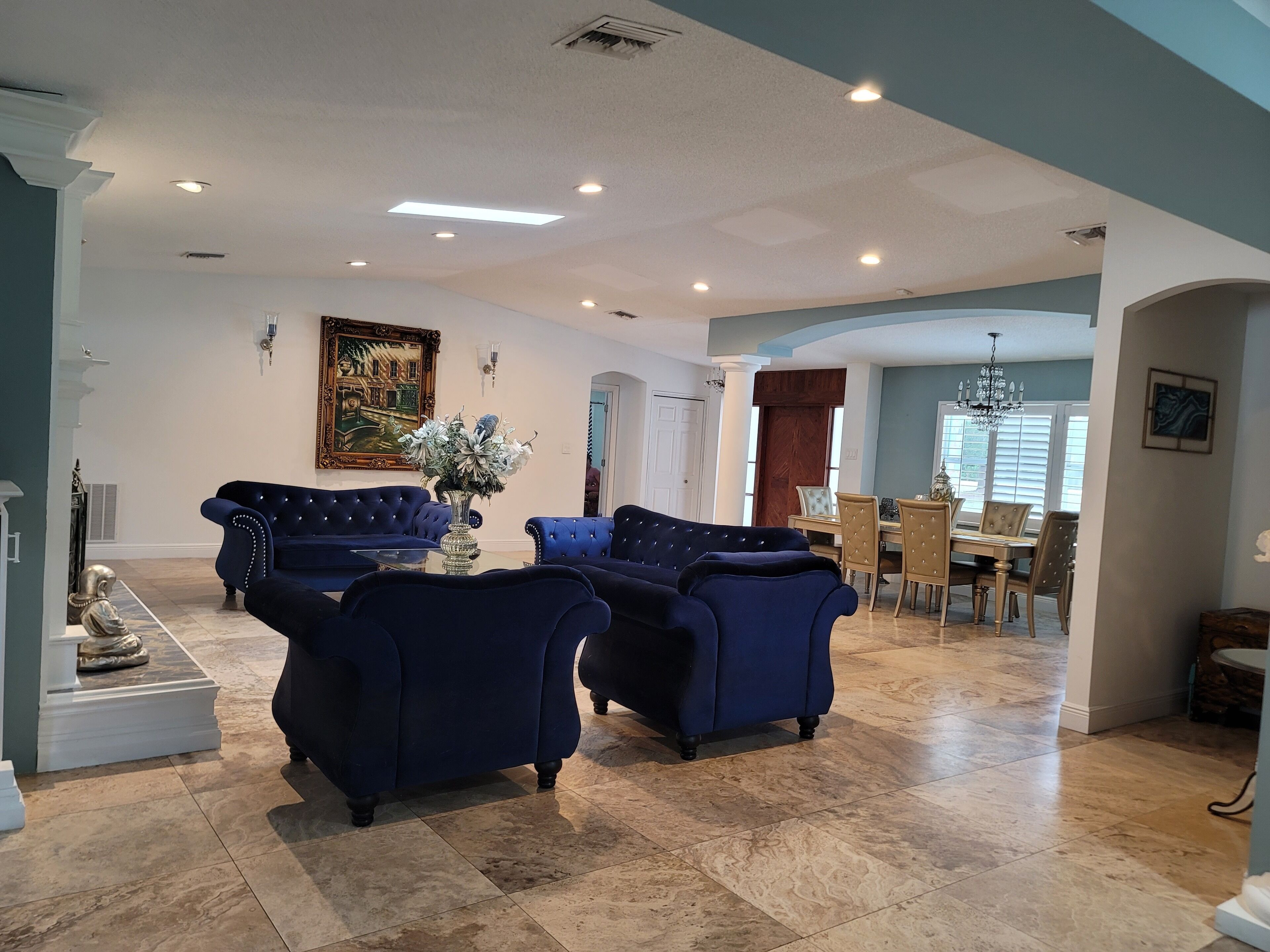 Un salon spacieux avec deux canapés bleus, une table basse et un coin repas comprenant des chaises et une table.