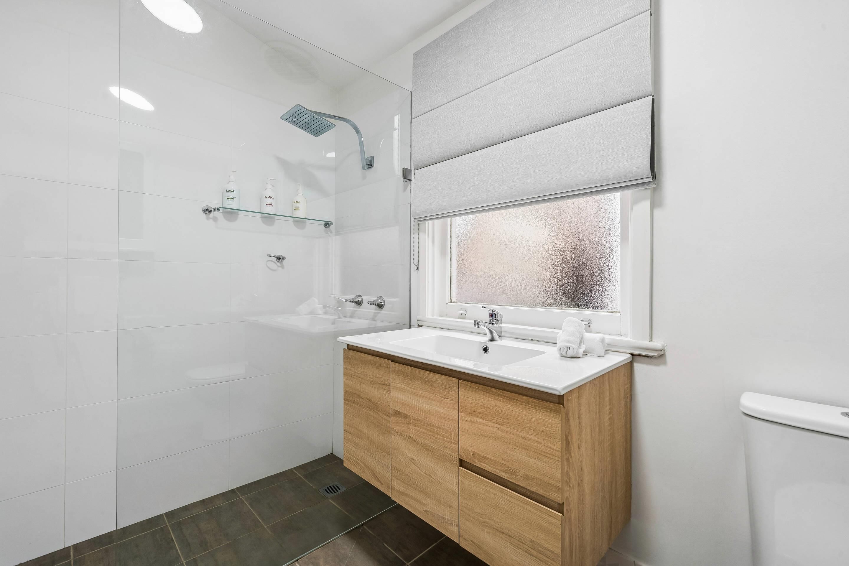 A modern bathroom with a shower, a sink, and a toilet.