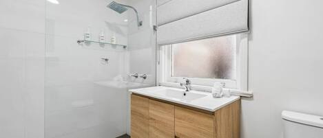 A modern bathroom with a shower, a sink, and a toilet.