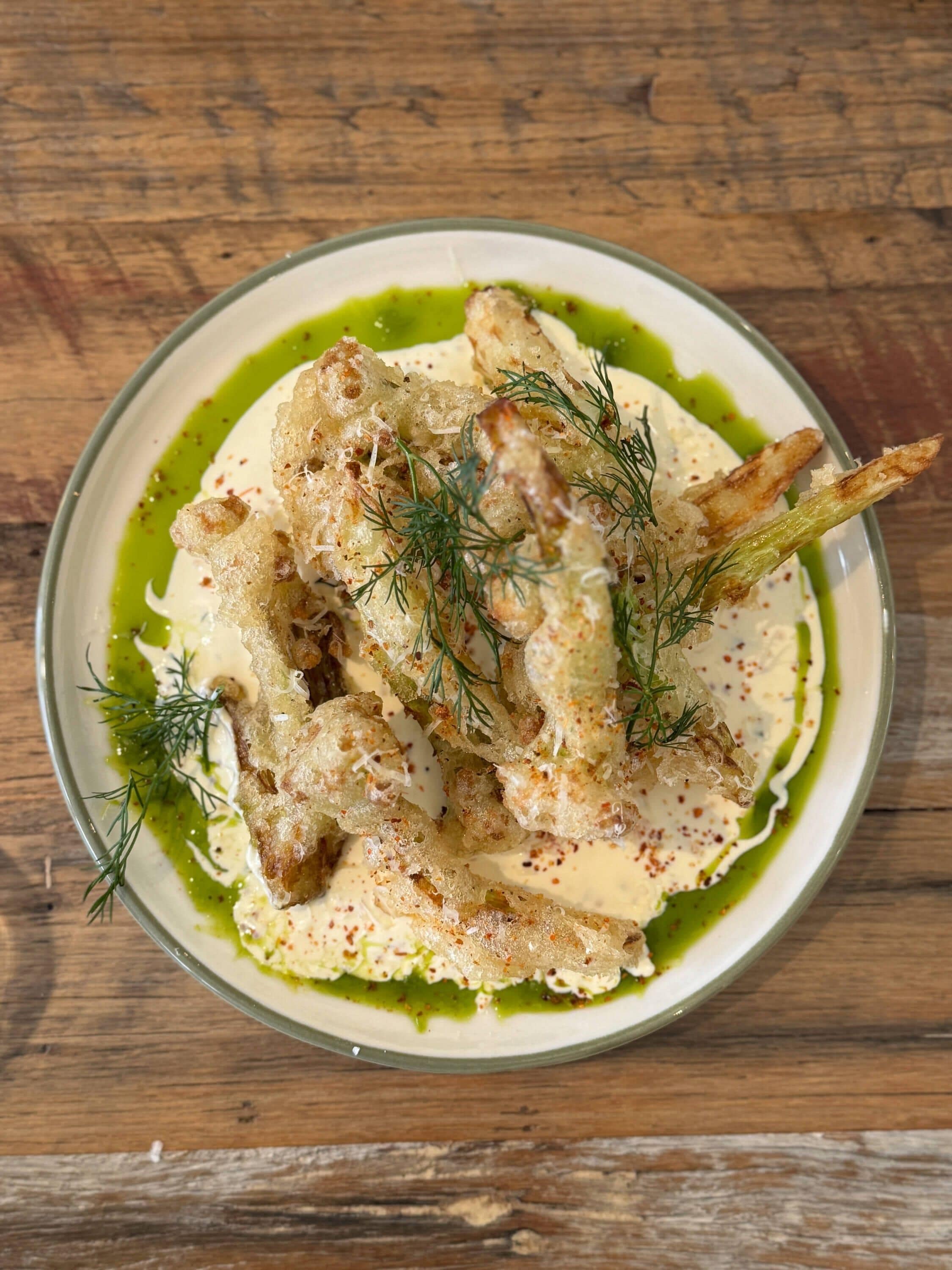 A plate of food with a green sauce, crispy bread, and a garnish of dill.
