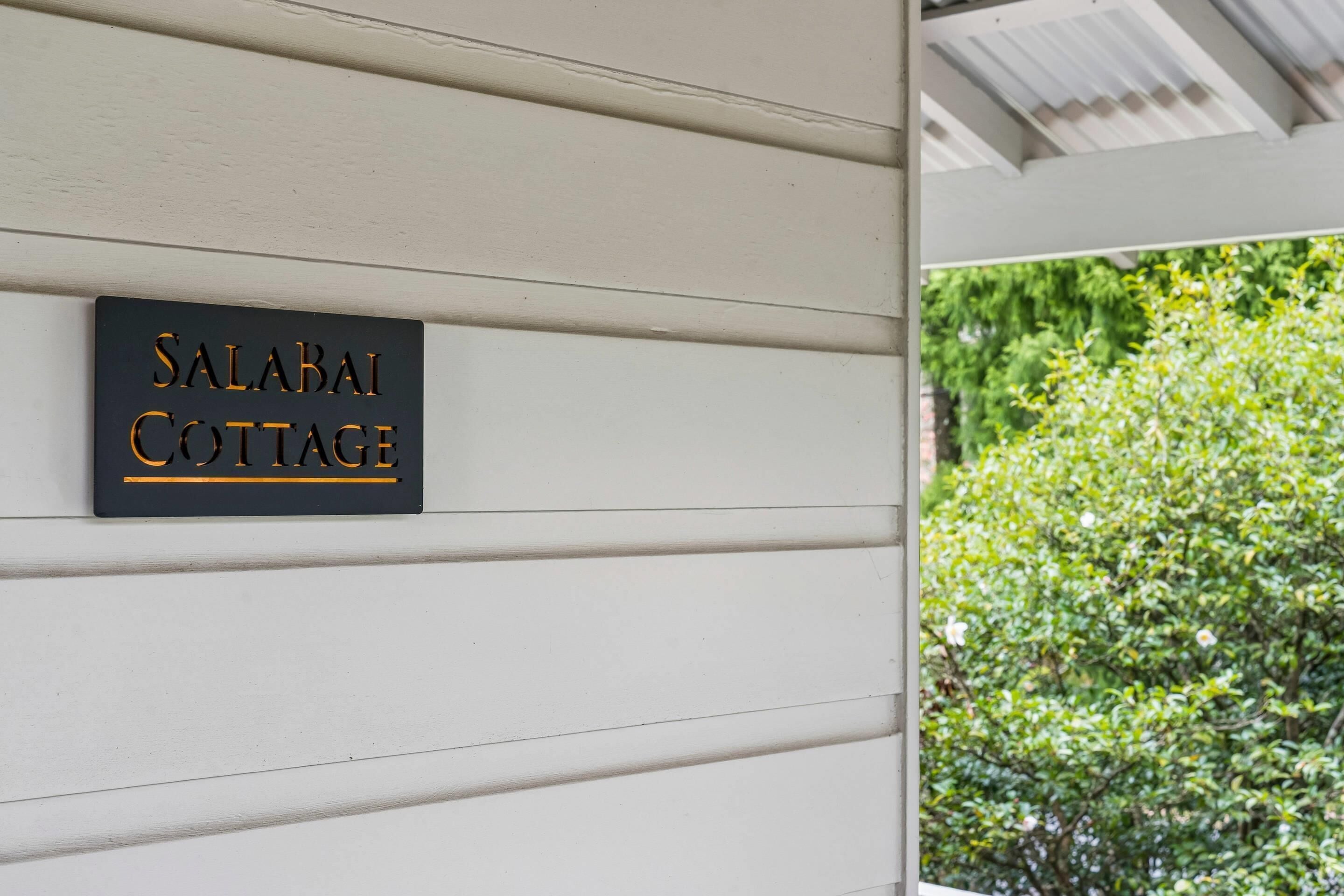 A sign on a white wall that reads 'SALABAI COTTAGE.'