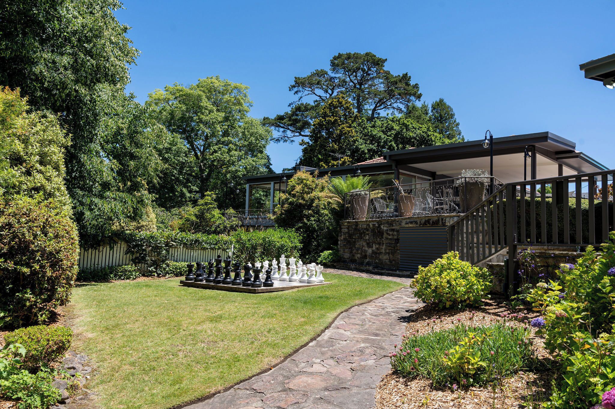 A garden with a chessboard, a covered patio, and a stone pathway.
