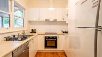 A compact kitchen with white cabinets, a stainless steel oven, a dishwasher, and a refrigerator.