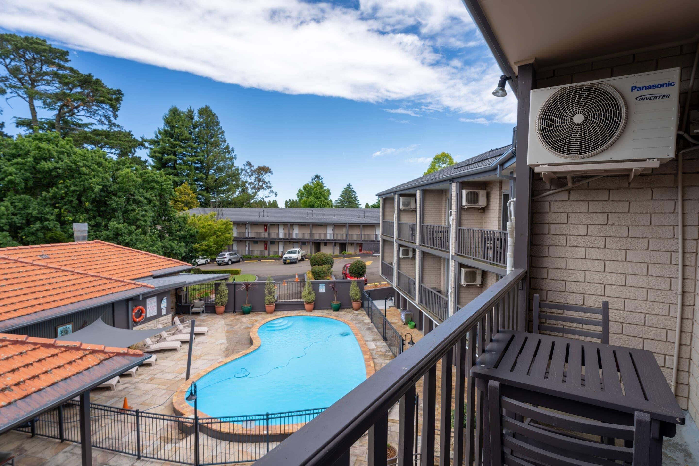 A residential building with a rooftop pool, outdoor seating, and a Panasonic air conditioning unit.