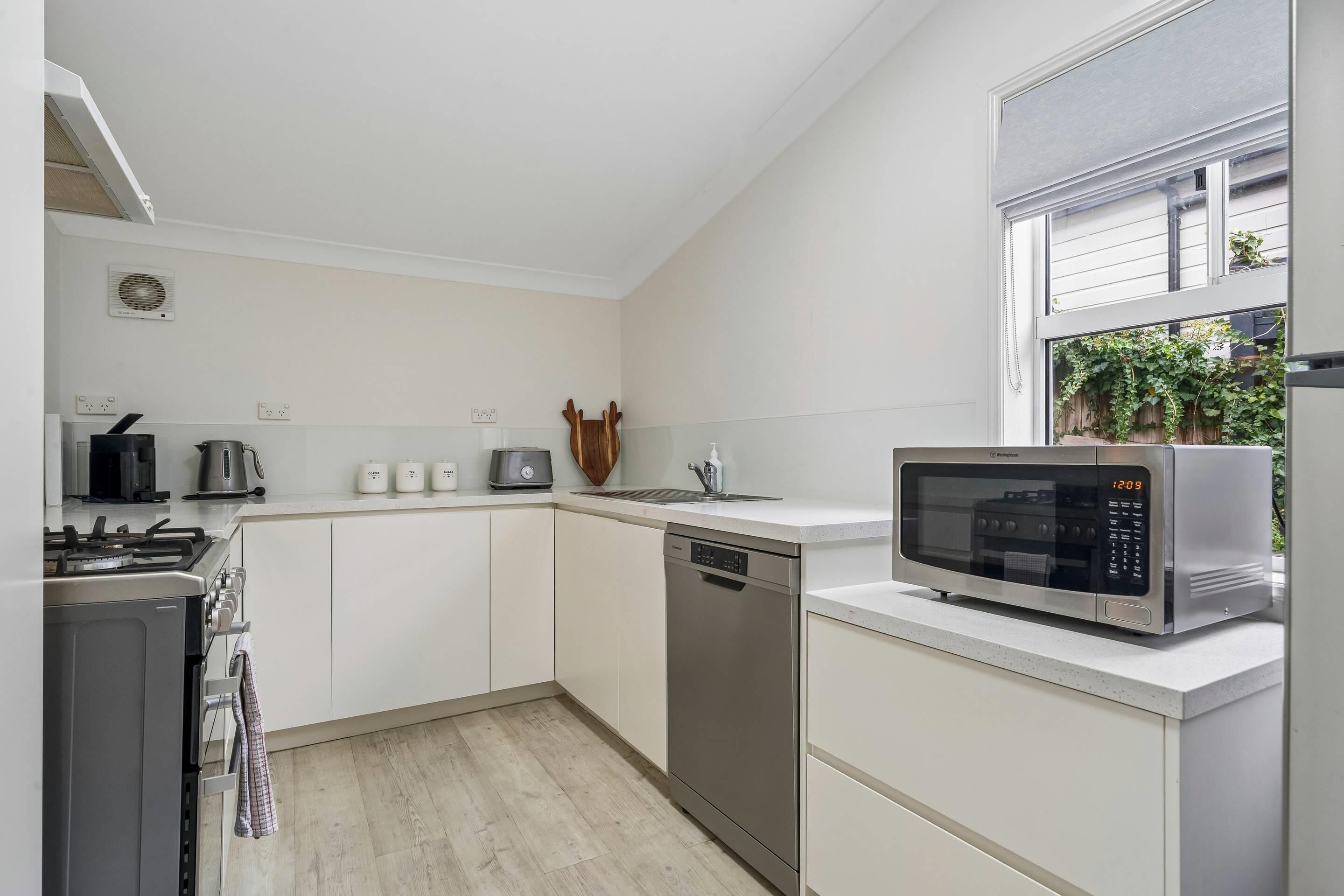 A modern kitchen with white cabinets, a stainless steel microwave, a dishwasher, and a gas stove.