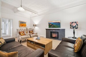 Una sala de estar con chimenea, sofás de cuero, una mesa de centro y un cuadro en la pared.