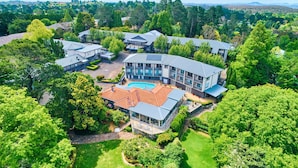 Een groot resort met meerdere gebouwen, een zwembad en weelderige begroeiing.