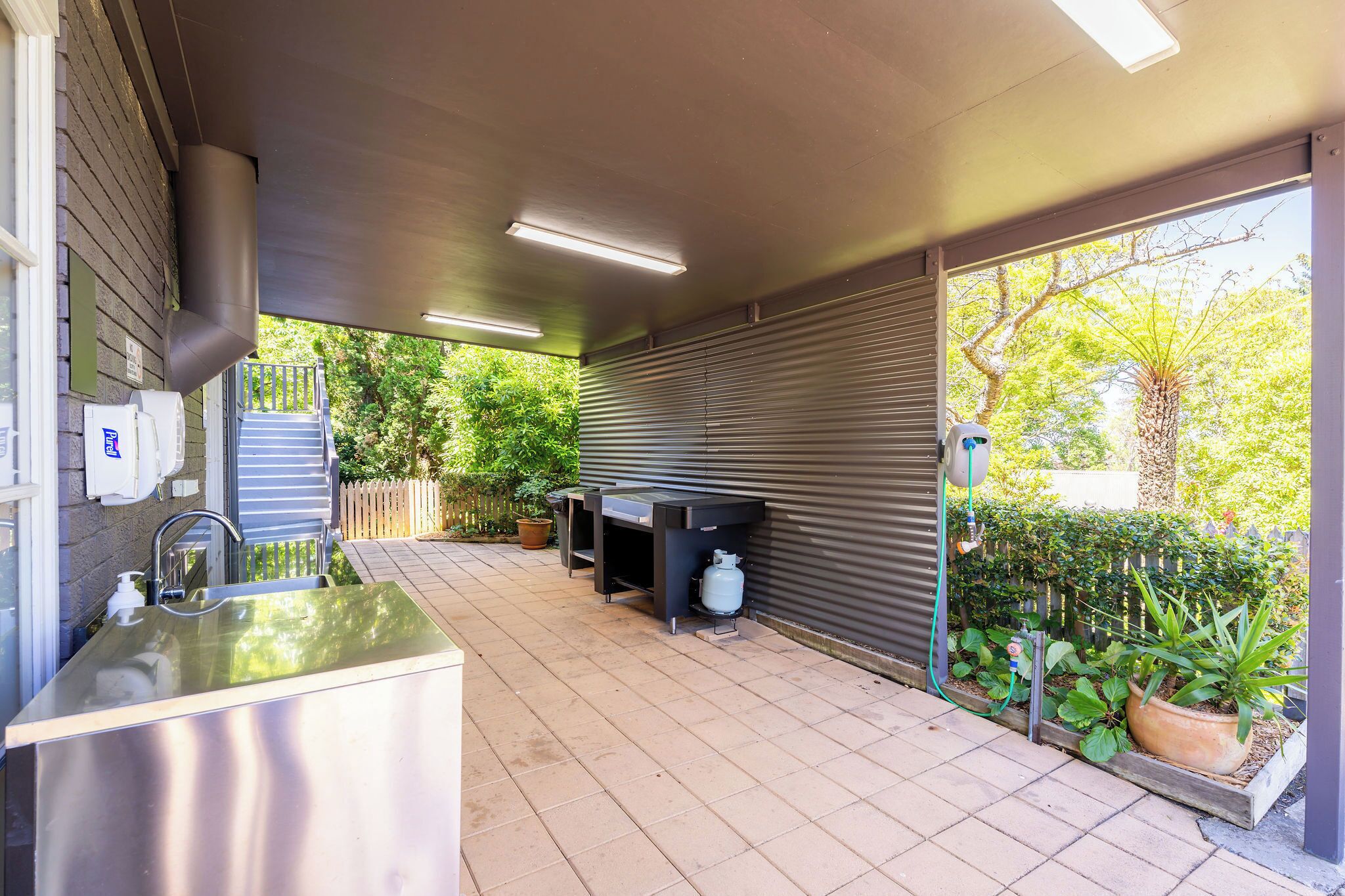 An outdoor kitchen area with a sink, a barbecue grill, and a gas cylinder.