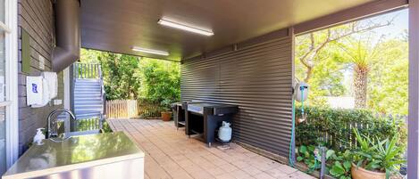 An outdoor kitchen area with a sink, a barbecue grill, and a gas cylinder.