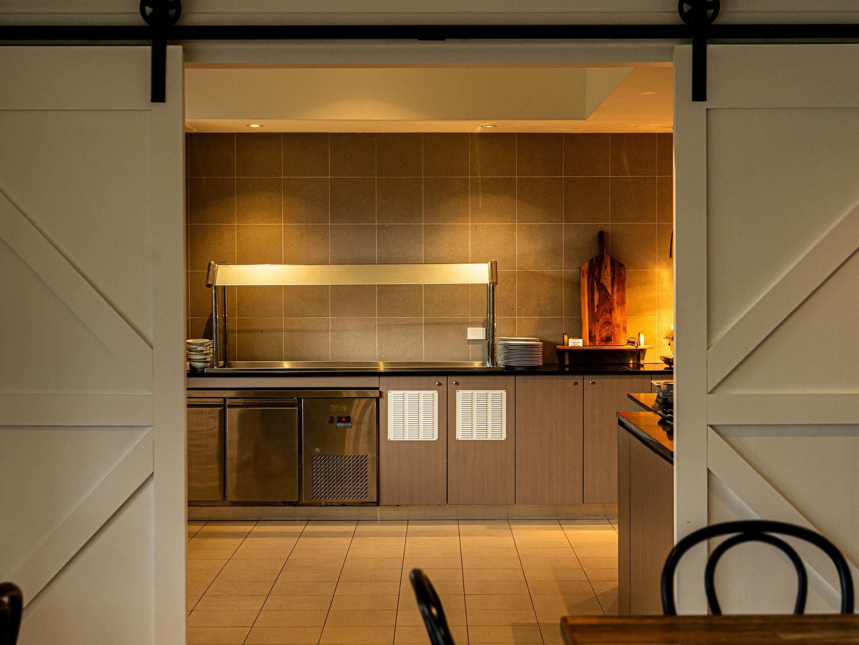 A modern kitchen with a large island, stainless steel appliances, and a wooden pizza oven.