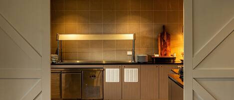 A modern kitchen with a large island, stainless steel appliances, and a wooden pizza oven.