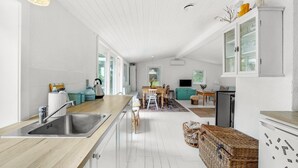 A modern kitchen with a wooden countertop, stainless steel sink, and a dining area with a wooden table and chairs.