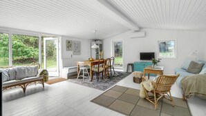 A spacious living room with a wooden dining table, a sofa, and a TV.