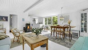 A spacious living room with a wooden dining table, a sofa, and a fireplace.