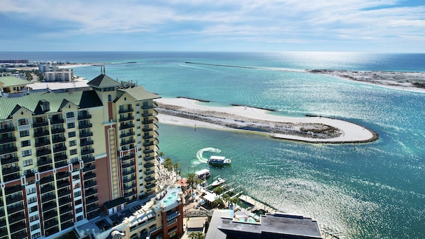 Un hôtel de grande hauteur doté de balcons donnant sur une plage et une marina.