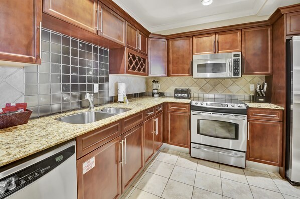 A kitchen with wooden cabinets, a stainless steel microwave, a double oven, and a dishwasher.