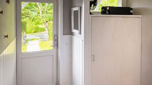Eine weiße Tür mit Fenster, ein weißes Schranksystem und ein kleines schwarzes Objekt darauf.