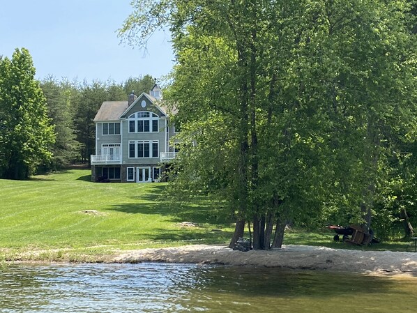A large two-story house with a wrap-around porch and a lawn in front.