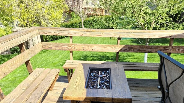En træterrasse med en stenpejs, bænke og et bord.