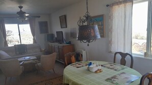 A dining area with a table set for two, a sofa, and a television in the background. - Wild Creek BnB, " Cottage " (Dyer)