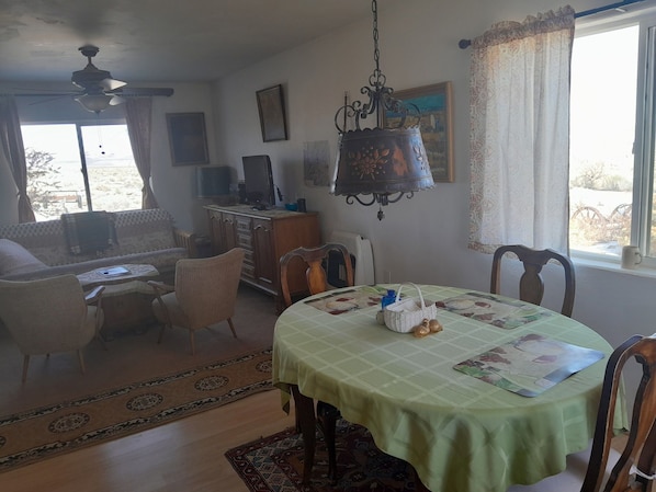 Un comedor con una mesa preparada para dos, un sofá y un televisor al fondo.