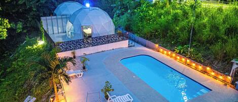 A swimming pool with lounge chairs, a small garden area, and two dome-shaped structures.
