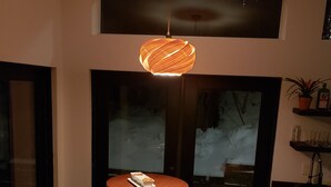 A modern dining area with a round table and two chairs, a hanging light fixture, and a view through a glass door. - The Tiny  Basecamp  (Flagstaff)