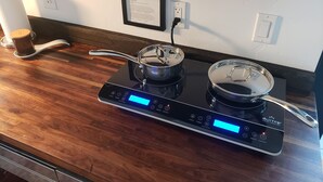 A modern kitchen with a black induction cooktop, two pots, and a digital display. - The Tiny  Basecamp  (Flagstaff)