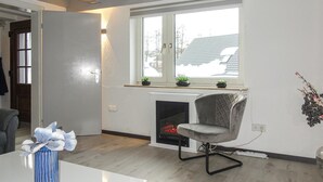 A modern living room with a fireplace, a window with plants, and a grey chair. - Nice home in Medebach with sauna (Medebach)