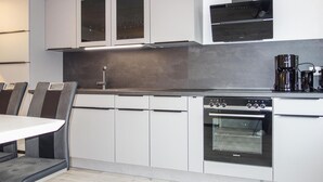 A modern kitchen with white cabinets, a built-in oven, and a coffee maker. - Nice home in Medebach with sauna (Medebach)