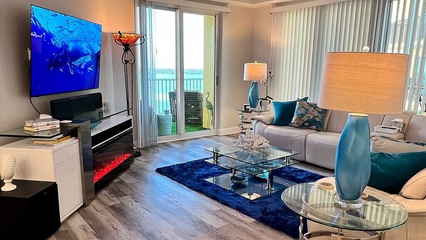Un salon moderne doté d’un téléviseur à écran plat, d’une table basse en verre, d’un canapé et d’un balcon offrant une vue agréable.