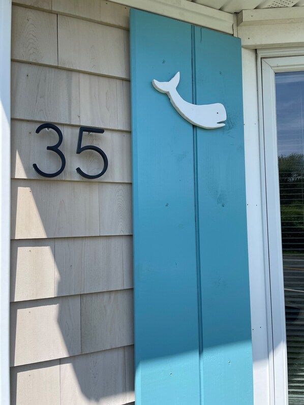 A house number 35 with a whale-shaped decoration on a teal door.