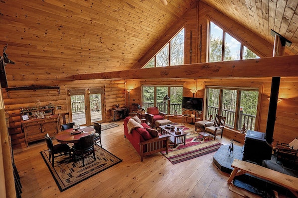 A log cabin interior with a dining area, living room, and a fireplace.