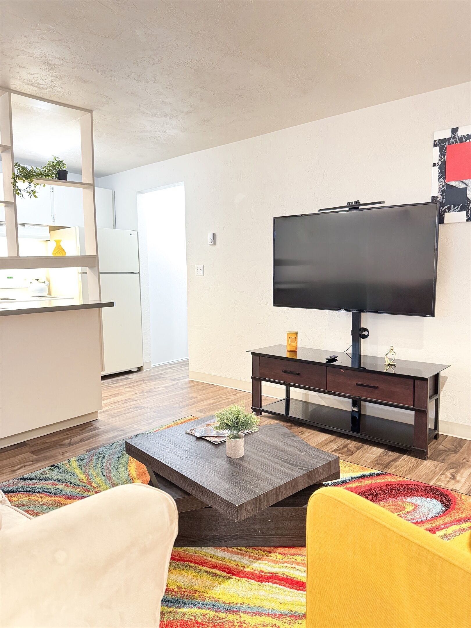 Una sala de estar moderna con un televisor de pantalla plana, una mesa de centro de madera oscura y una alfombra colorida.