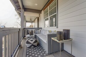 Relax in a serene outdoor space with a comfortable sofa and ottoman, surrounded by a patterned rug and decorative accents.