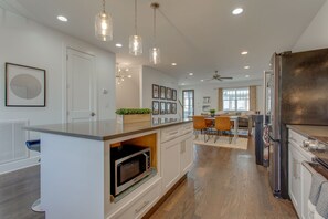 Enjoy meals in the well-lit kitchen with a central island, microwave, and stainless steel refrigerator.