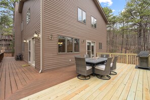 Ett tvåvåningshus med en veranda, utemöbler och en grill.