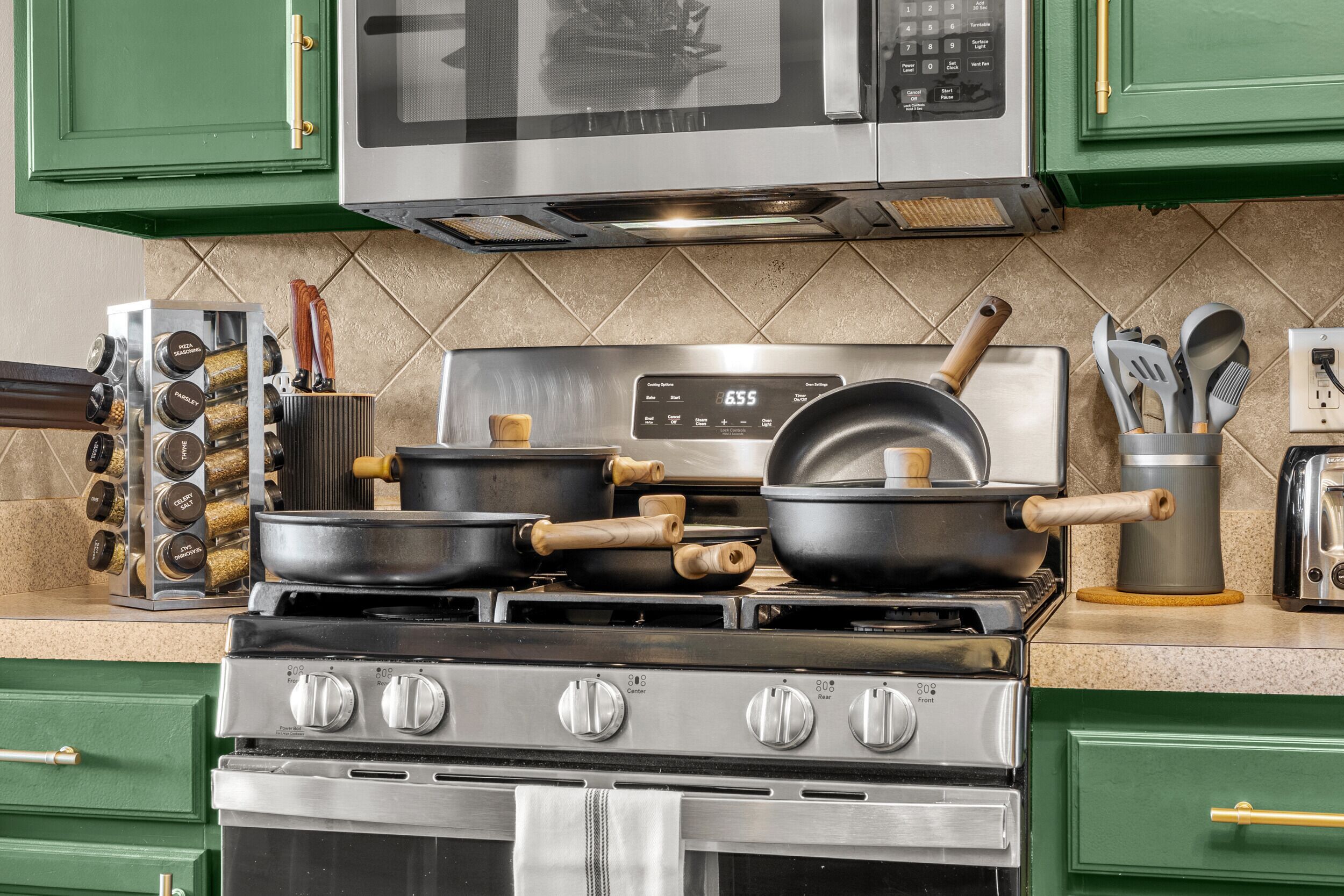 A kitchen with a stove, pots, and a microwave.